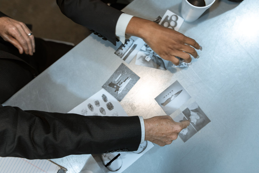 pair of hands interacting with detective case file evidence spread on a table